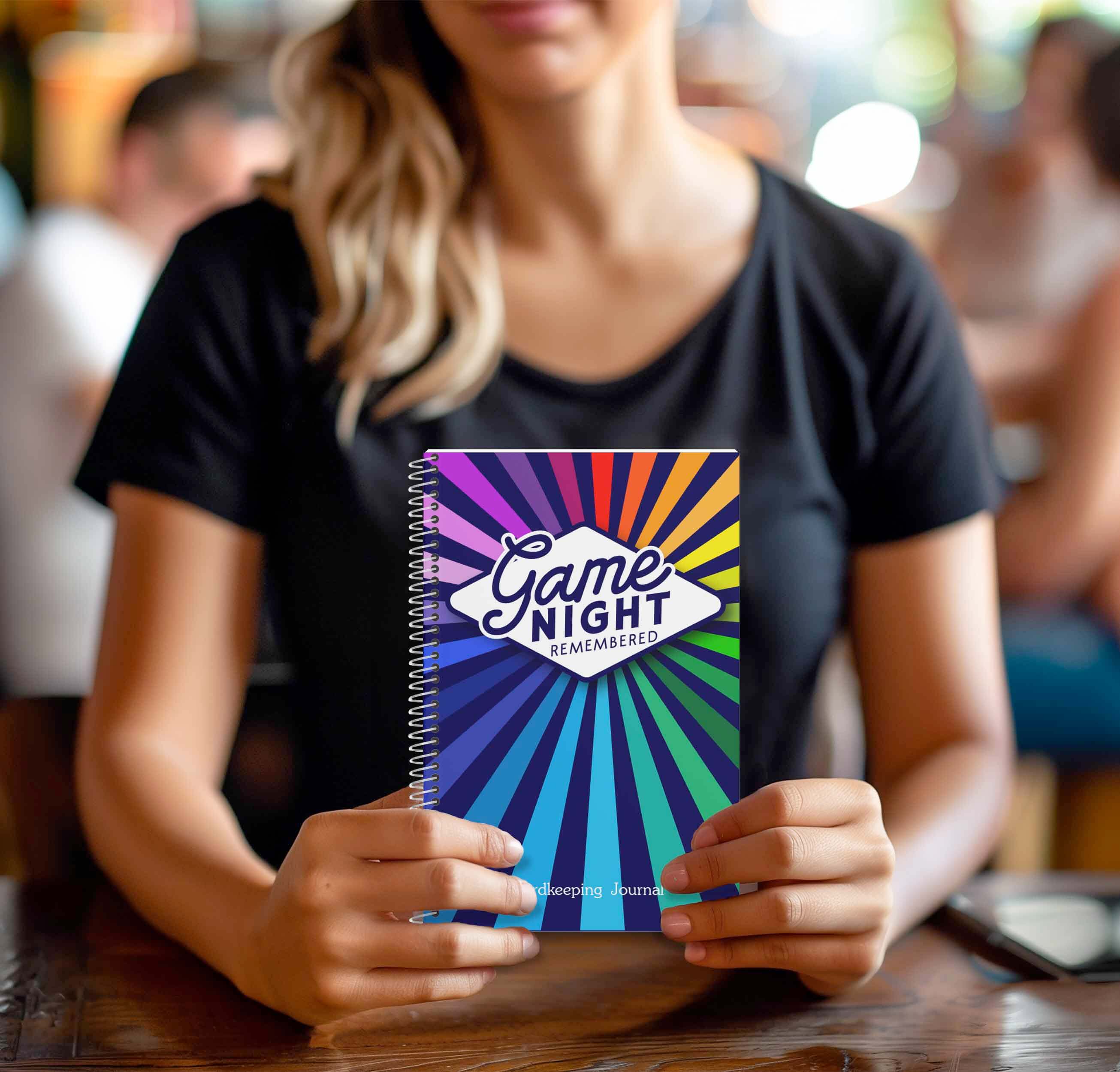 Person holding the Game Night Remembered journal with colorful design, perfect for tracking board games.