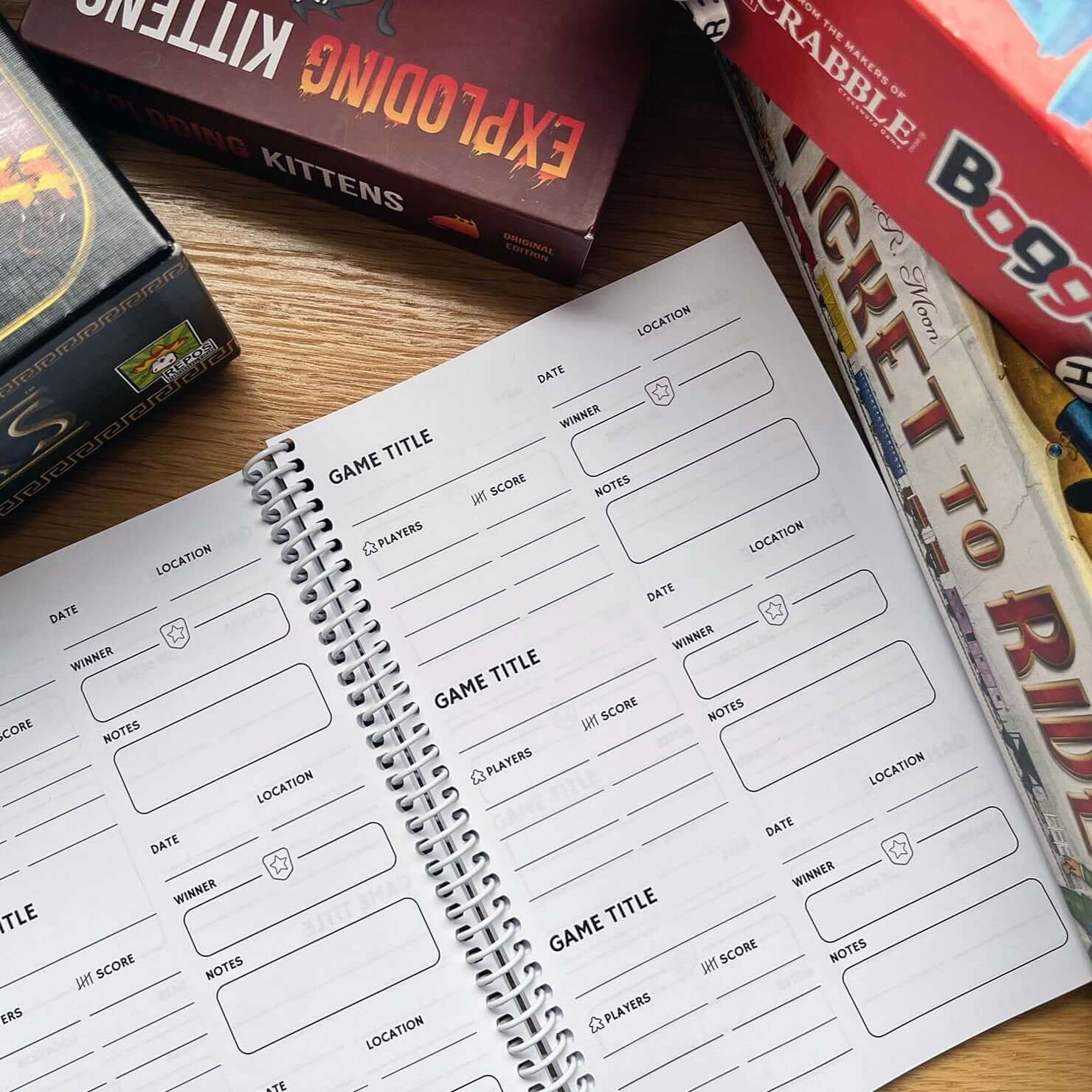 Open Board Game Journal pages for recording game details, surrounded by popular board game boxes.